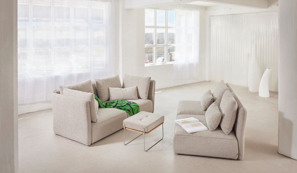 Modulares Sofa NICA von Yvi Living in heller Stoffausführung – zwei frei kombinierbare Sitzeinheiten mit Hocker und Rückenkissen, inszeniert in lichtdurchflutetem Raum mit modernem, minimalistischem Interieur.
