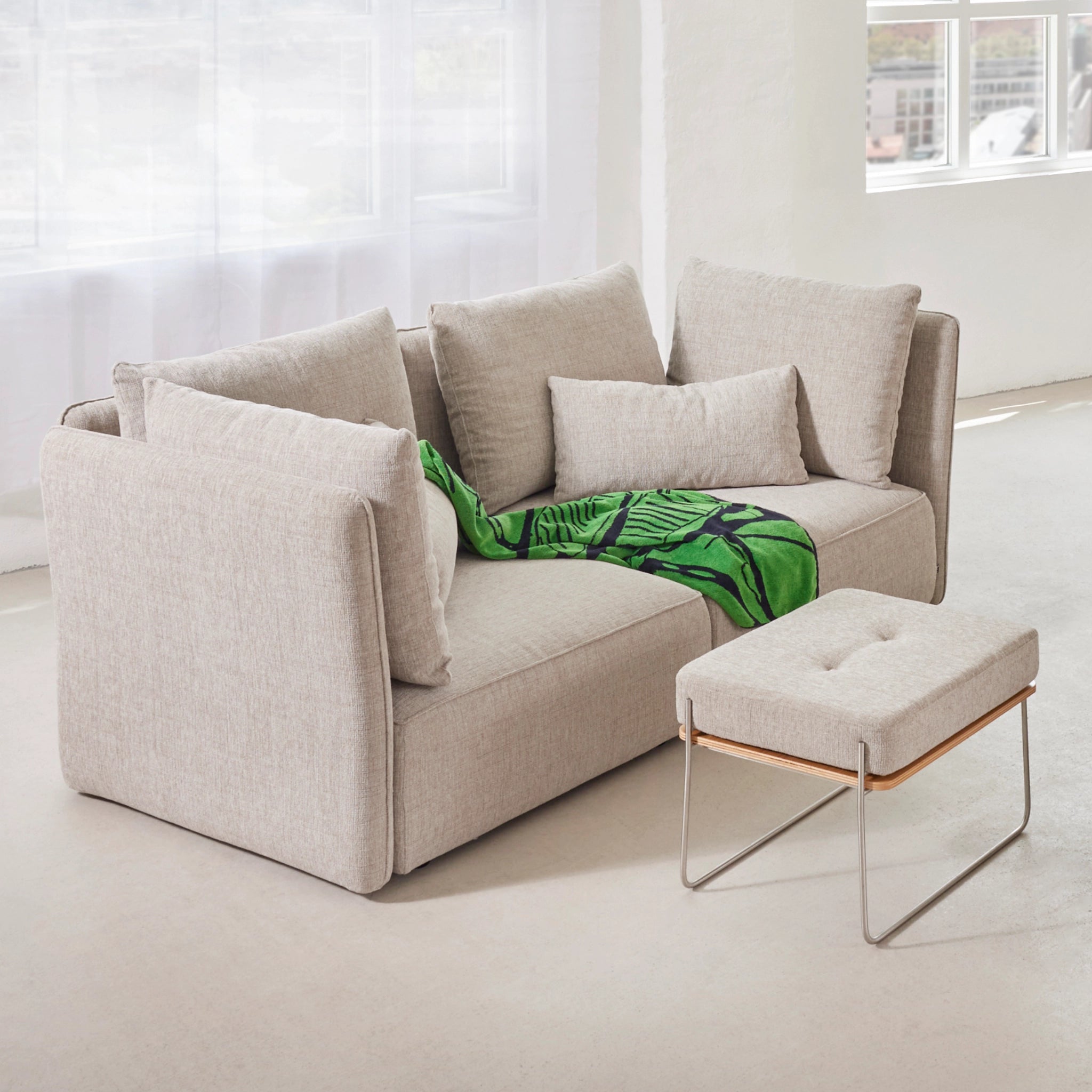 Helles Wohnzimmer mit 2-Sitzer-Sofa NICA von Yvi Living in Naturfarbe, kombiniert mit Hocker und grüner Decke – stilvolles Design trifft nachhaltige Gemütlichkeit im skandinavisch inspirierten Ambiente.