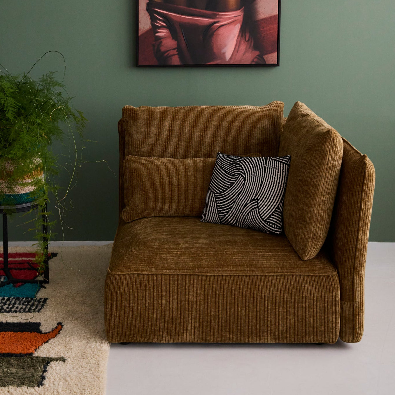 Sofa Nica Eckelement mit Stoff Breitcord in Farbe goldbraun. Die beiden hohen Rücken- und Seitenpolster formen eine schützende Ecke, in der die weiche Sitzfläche und die beiden Kissen ruhig wirken. Das Element steht frei im Raum und ist durch seine markante Form deutlich hervorgehoben.