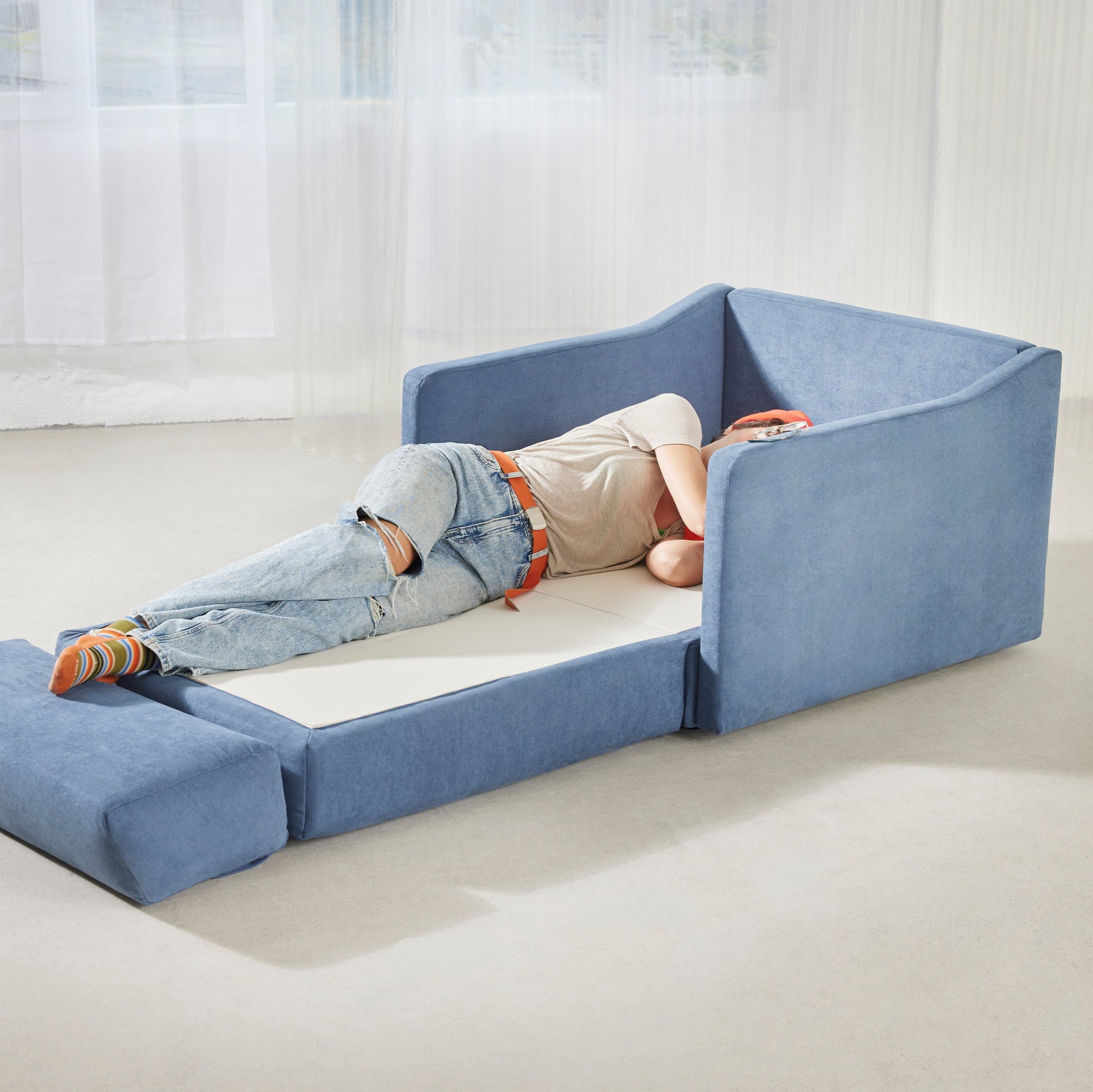 Schlafsessel ERNST in der Farbe blau ausgeklappt. Auf dem Schlafsessel liegt eine Person und schläft auf dem Schlafsessel.