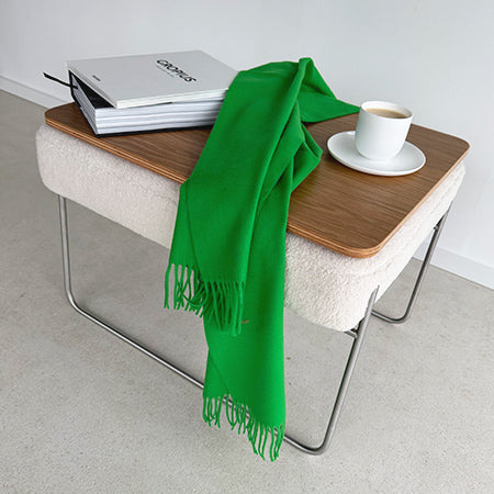 Beistelltisch „Prop!Up“ von Yvi Living mit heller Polsterung und Holzplatte, dekoriert mit grünem Schal, Buch und Kaffeetasse auf hellem Boden.