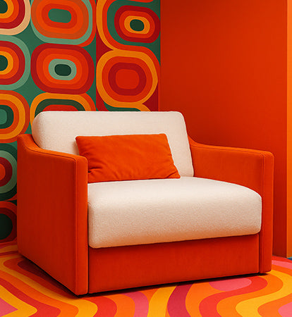 Schlafsessel „Ernst“ von Yvi Living in leuchtendem Orange mit cremefarbener Sitzfläche – Retro-Design mit 70er-Jahre-Muster im Hintergrund.
